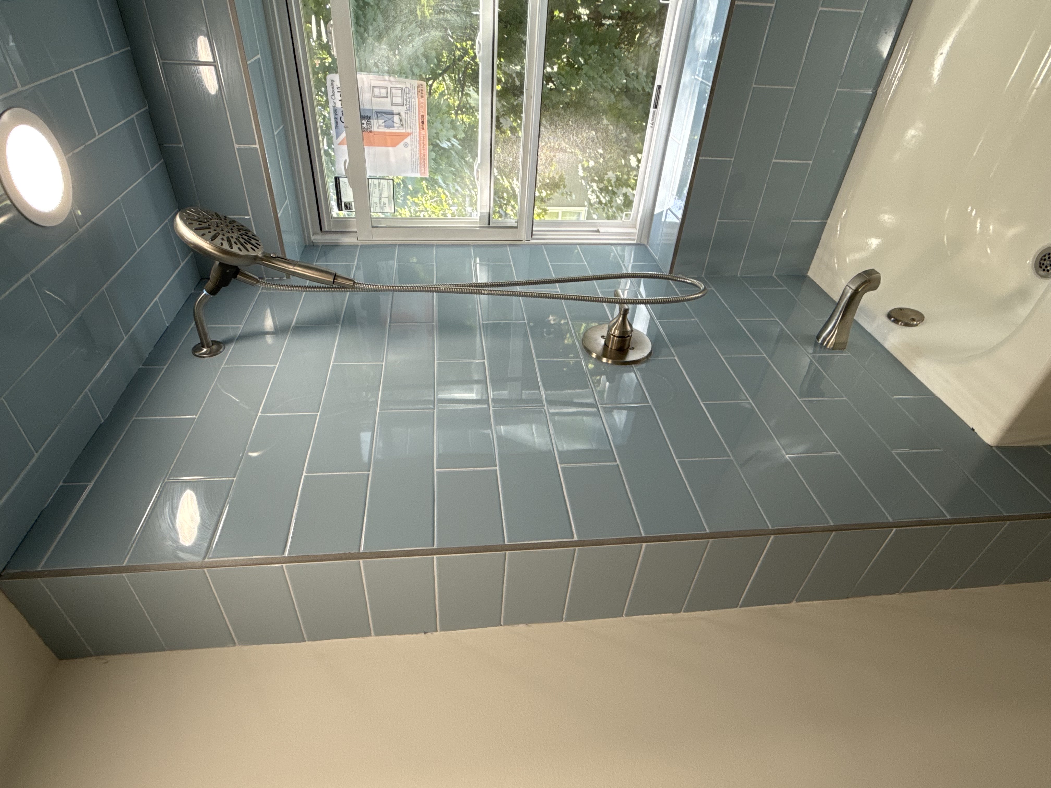 Bathroom featuring a white bathtub, light blue subway tiles, chrome fixtures, and a new window after bathroom remodeling in [City], NJ.