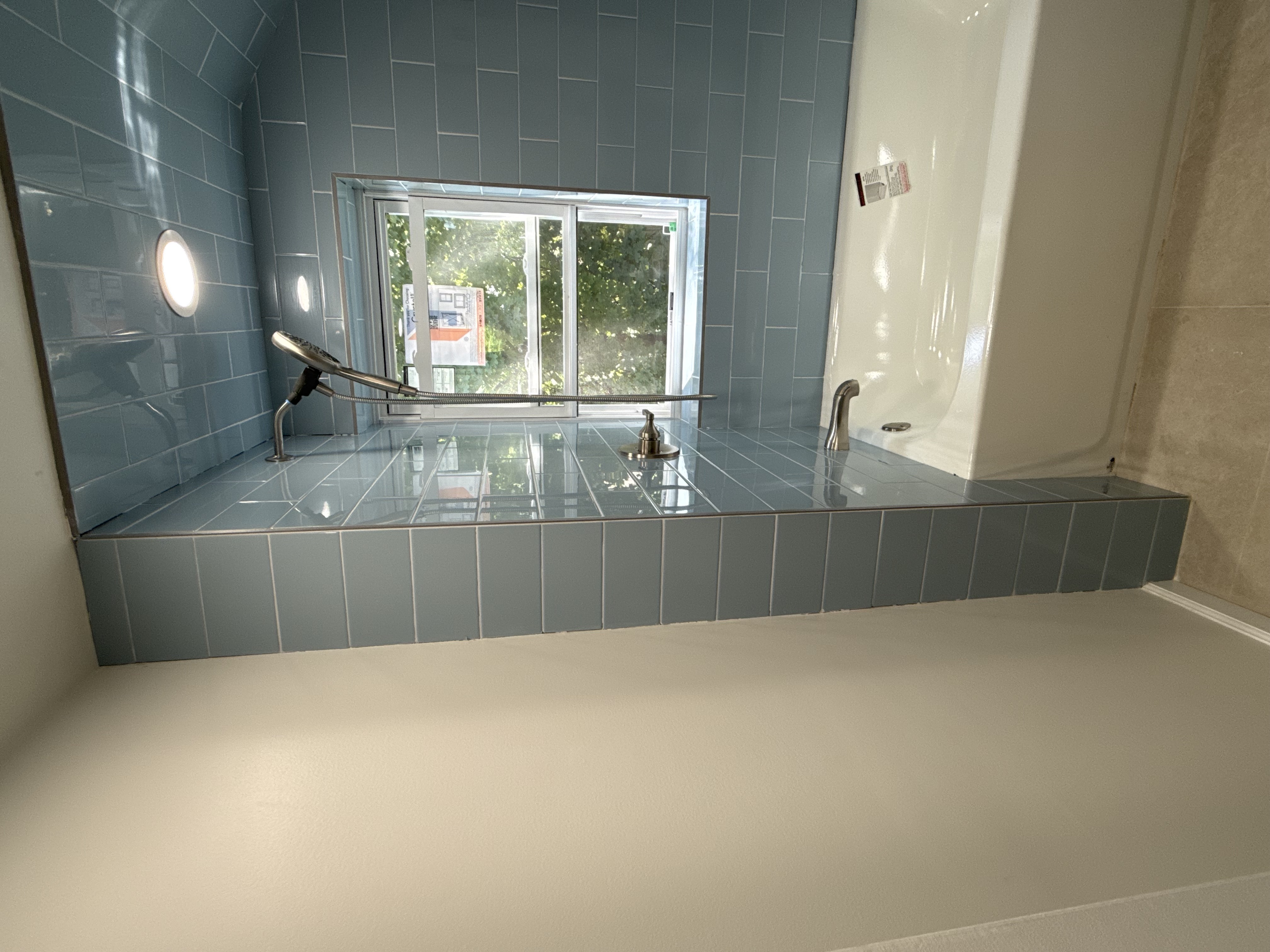 Contemporary bathroom featuring light blue subway tile, white tub, brushed nickel fixtures, and recessed lighting after bathroom renovation in , NJ.