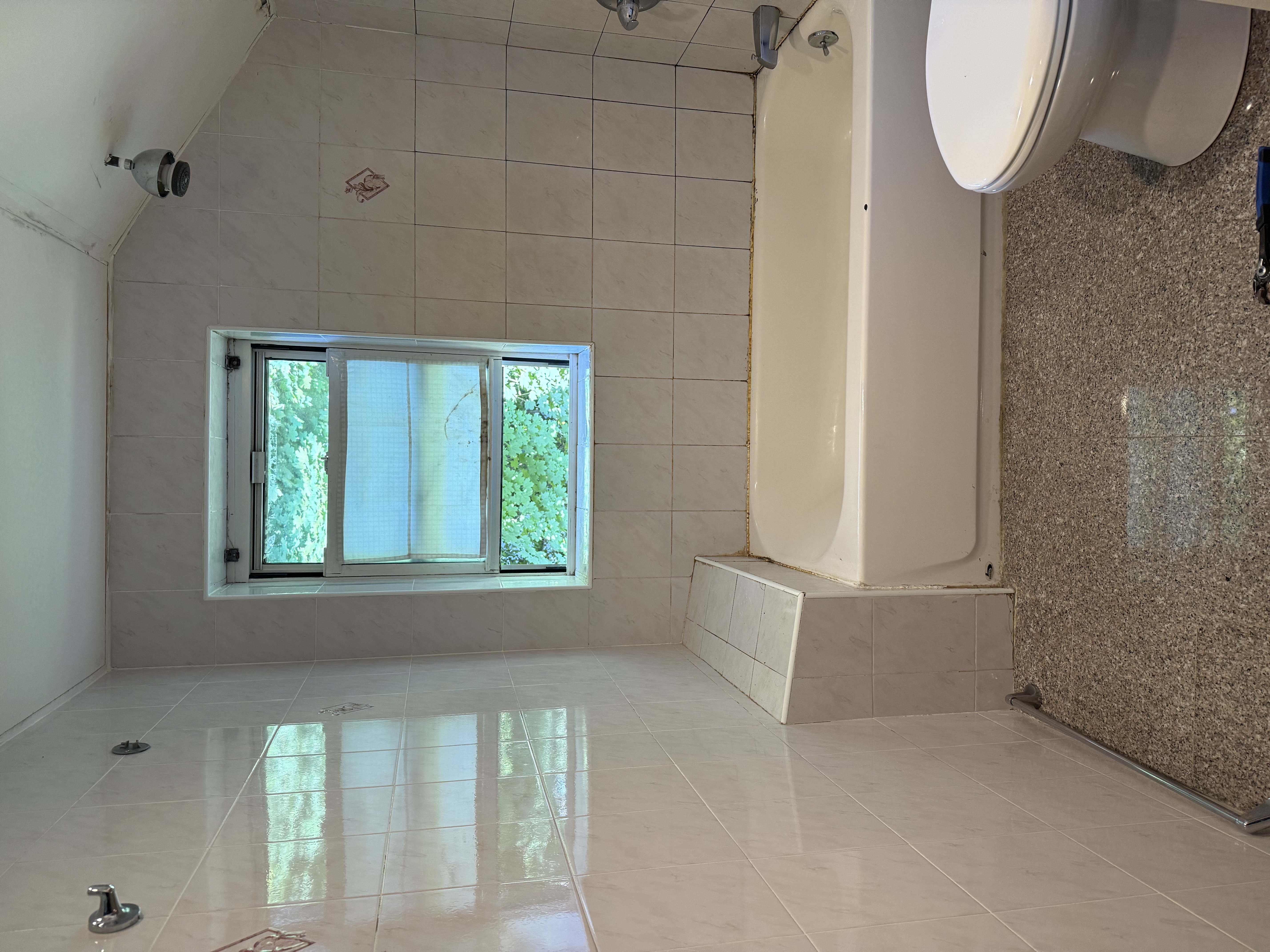 Bathroom featuring dated beige wall tiles, built-in tiled bench, bathtub, and toilet. Needs renovation in , NJ.