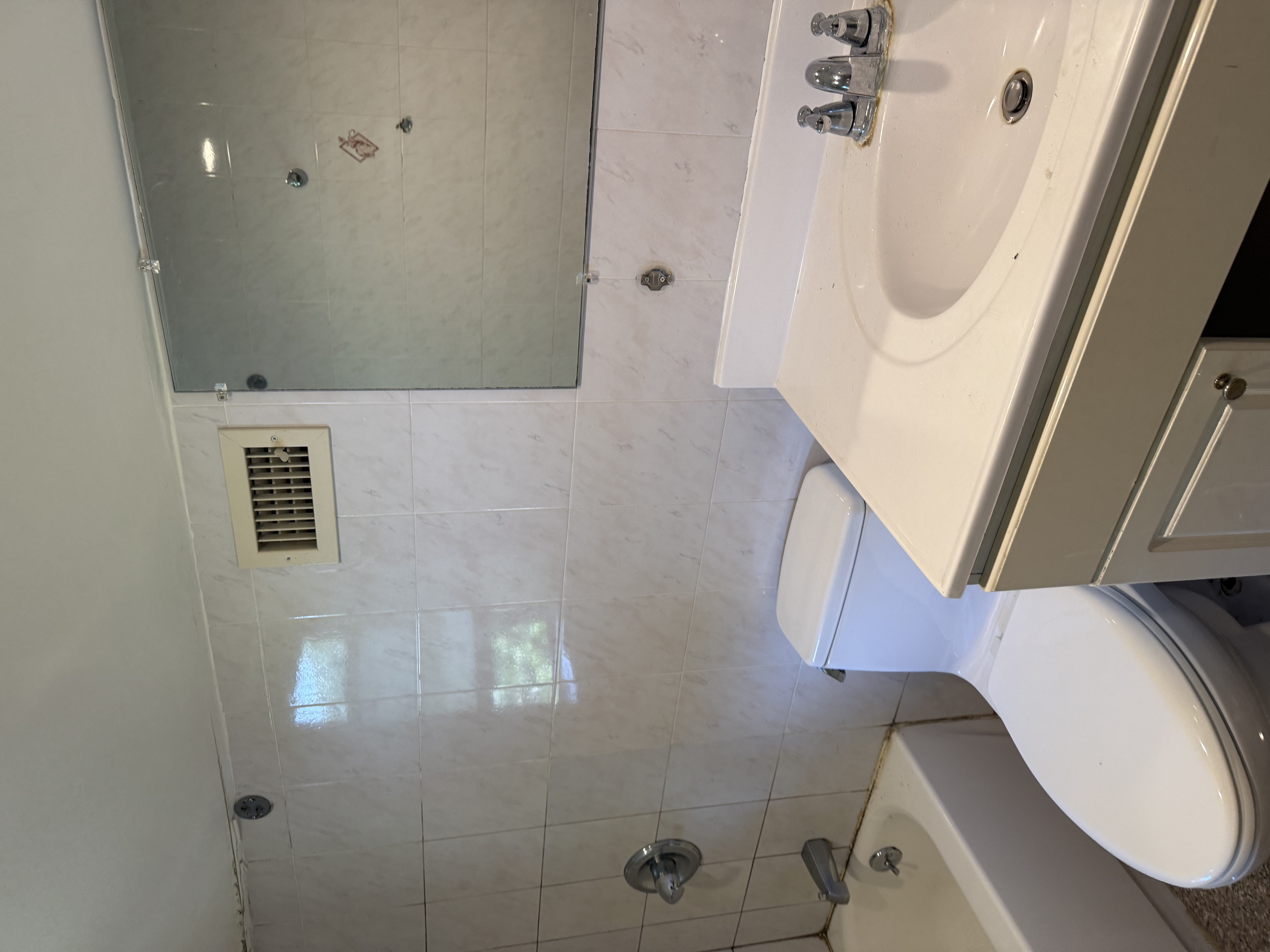 Bathroom with white tiled walls, white vanity, new toilet & tub after bathroom renovation in [City], NJ.