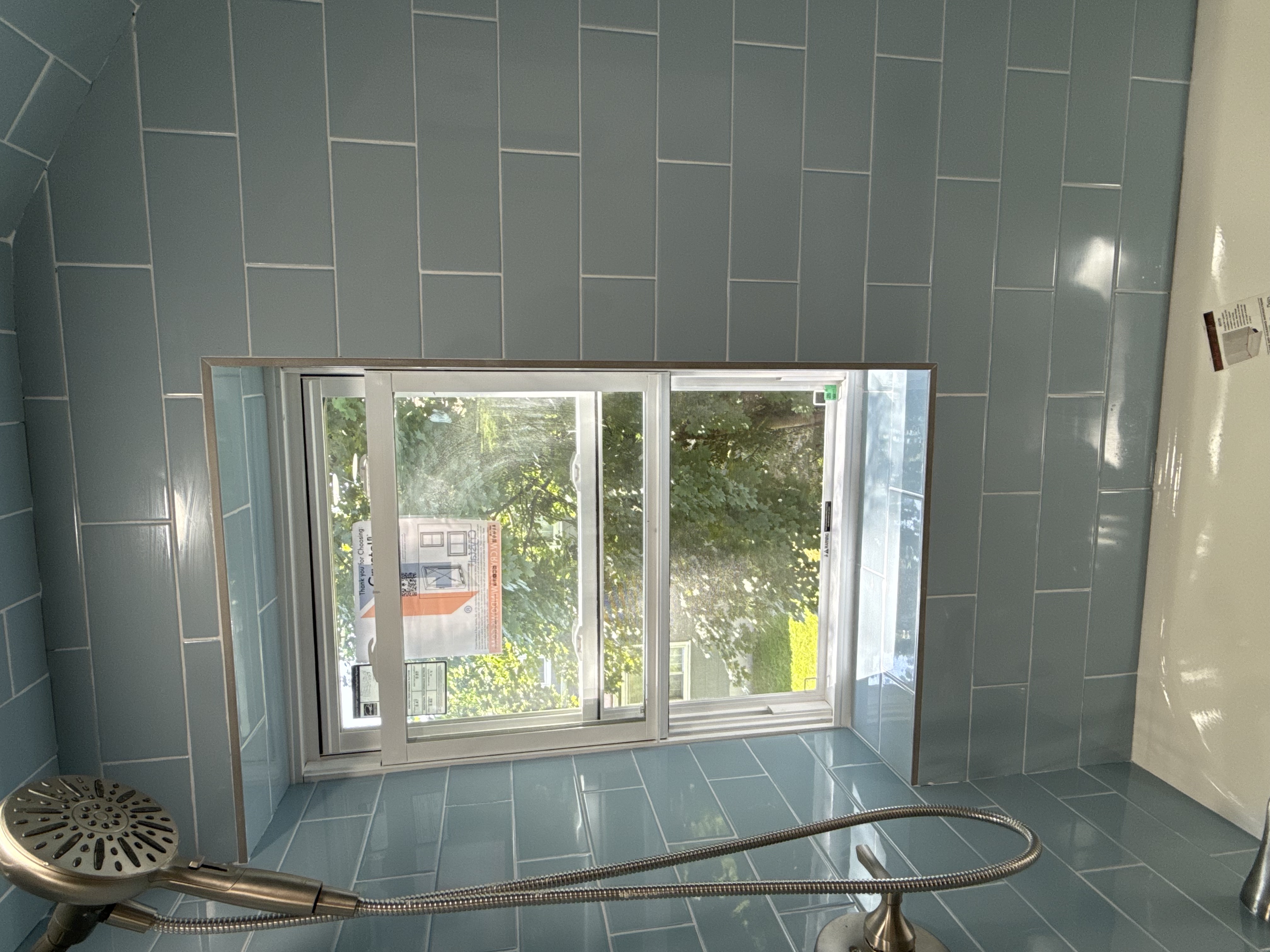 Bathroom featuring blue subway tile, brushed nickel showerhead, and window after full bathroom renovation in , NJ