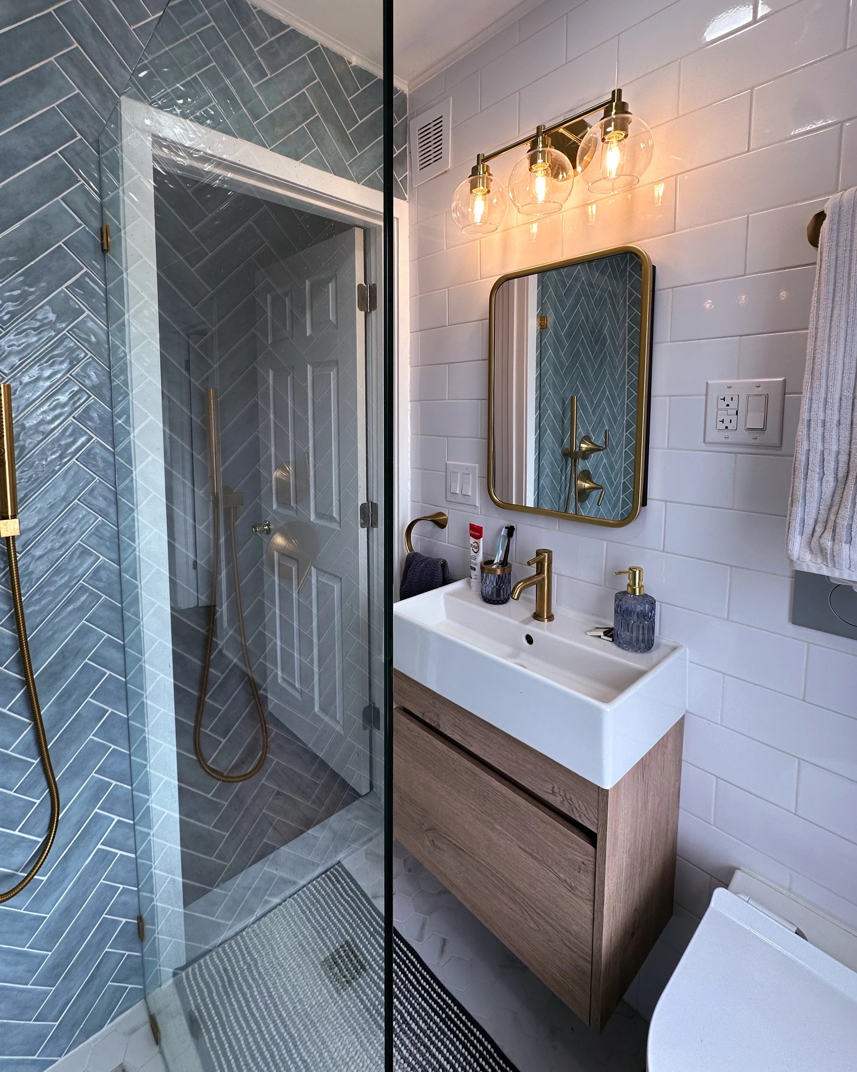 Modern bathroom with blue subway tile shower, white subway tile walls, wood vanity, and gold fixtures after Bathroom Renovation in Rahway, NJ