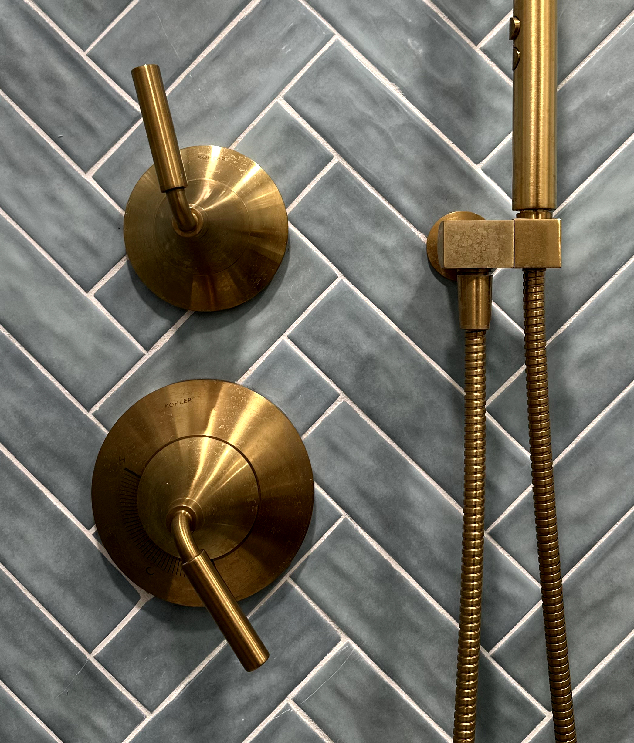Bathroom featuring blue herringbone subway tile & brass Kohler fixtures after Bathroom Renovation in Rahway, NJ, NJ.