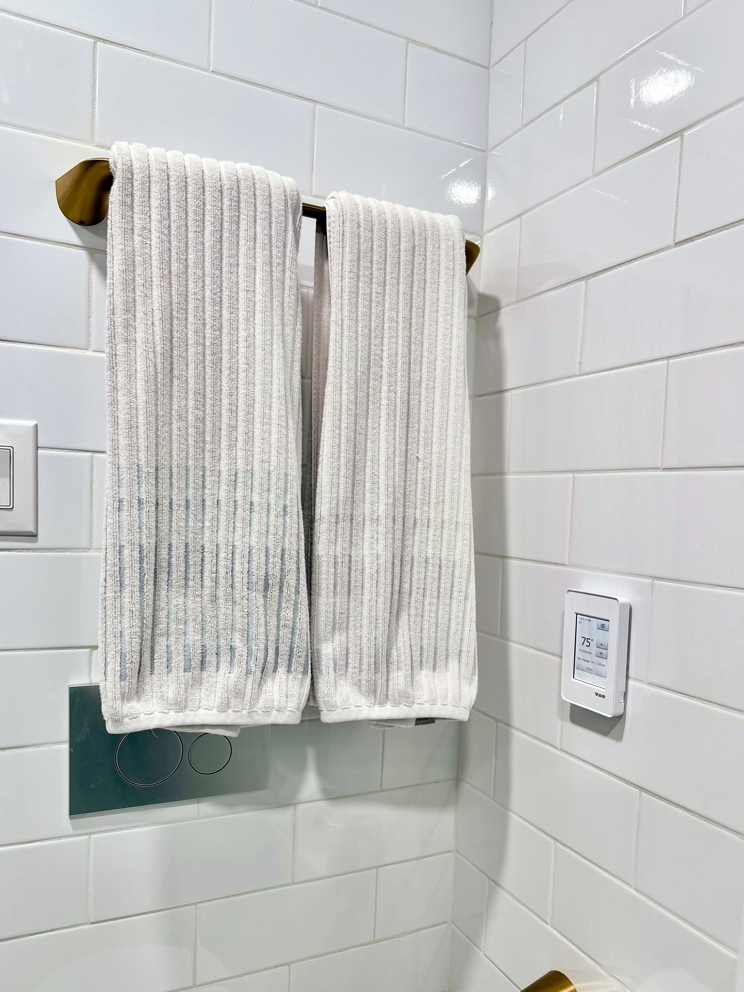 Bathroom featuring white subway tile walls, a brass towel rack, and smart thermostat for heated flooring after Bathroom Renovation in Rahway, NJ.