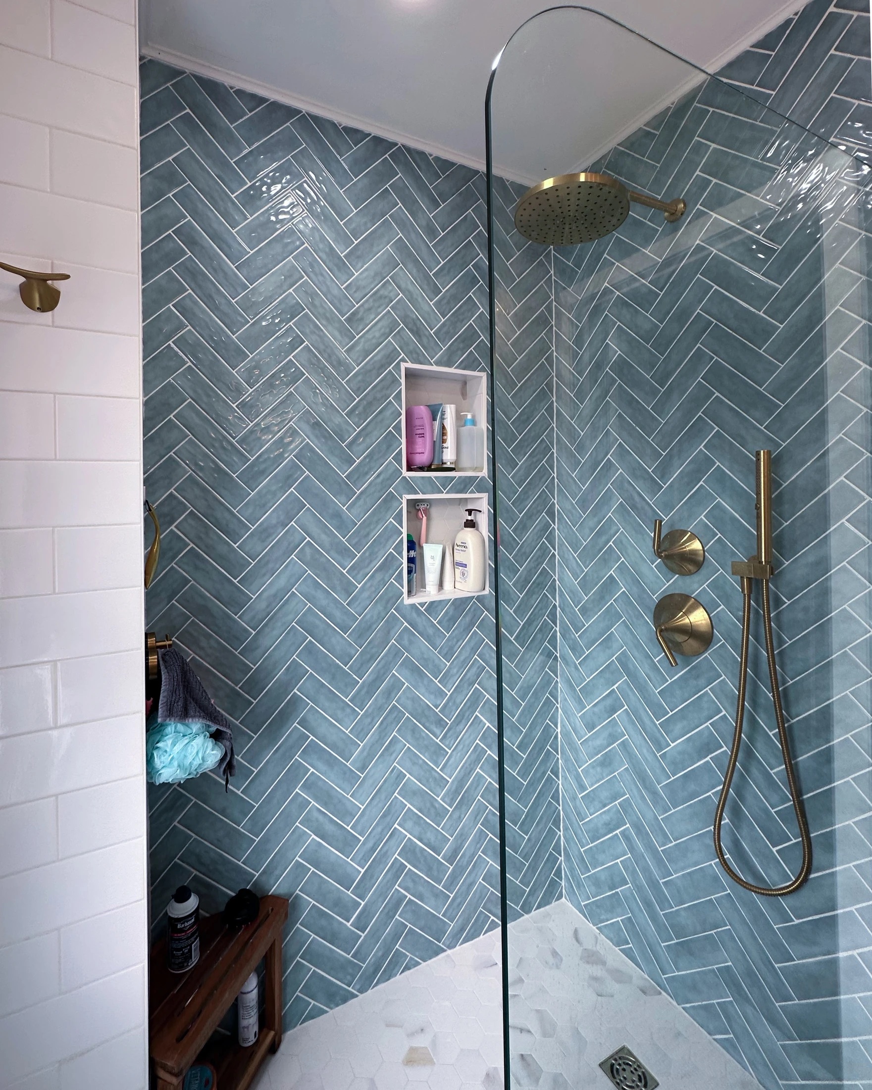 Walk-in shower with blue herringbone tiles, white subway tile accent, and brass fixtures after Bathroom Renovation in Rahway, NJ.