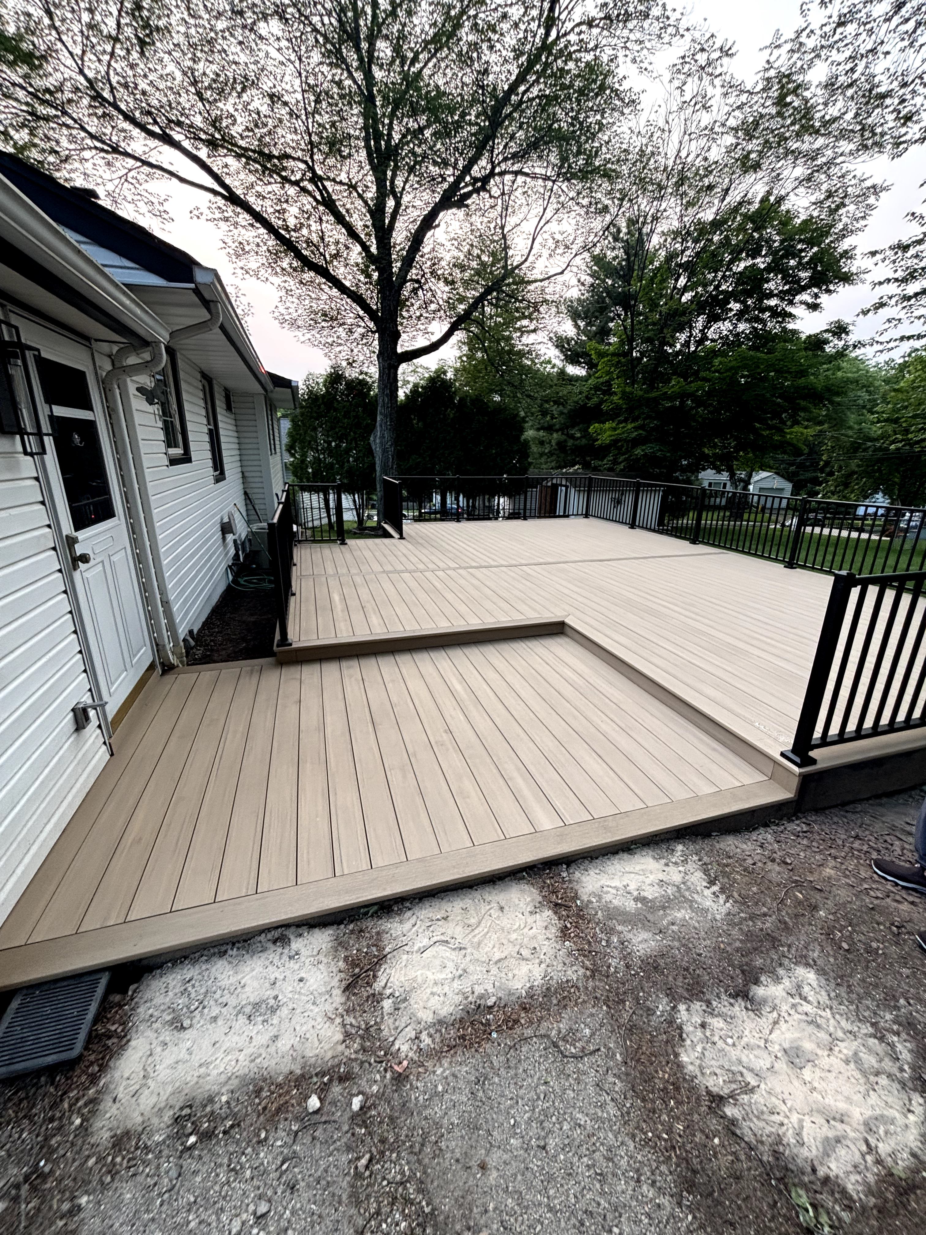 Outdoor deck featuring new light brown composite decking with black railings in Cedar Grove, NJ.