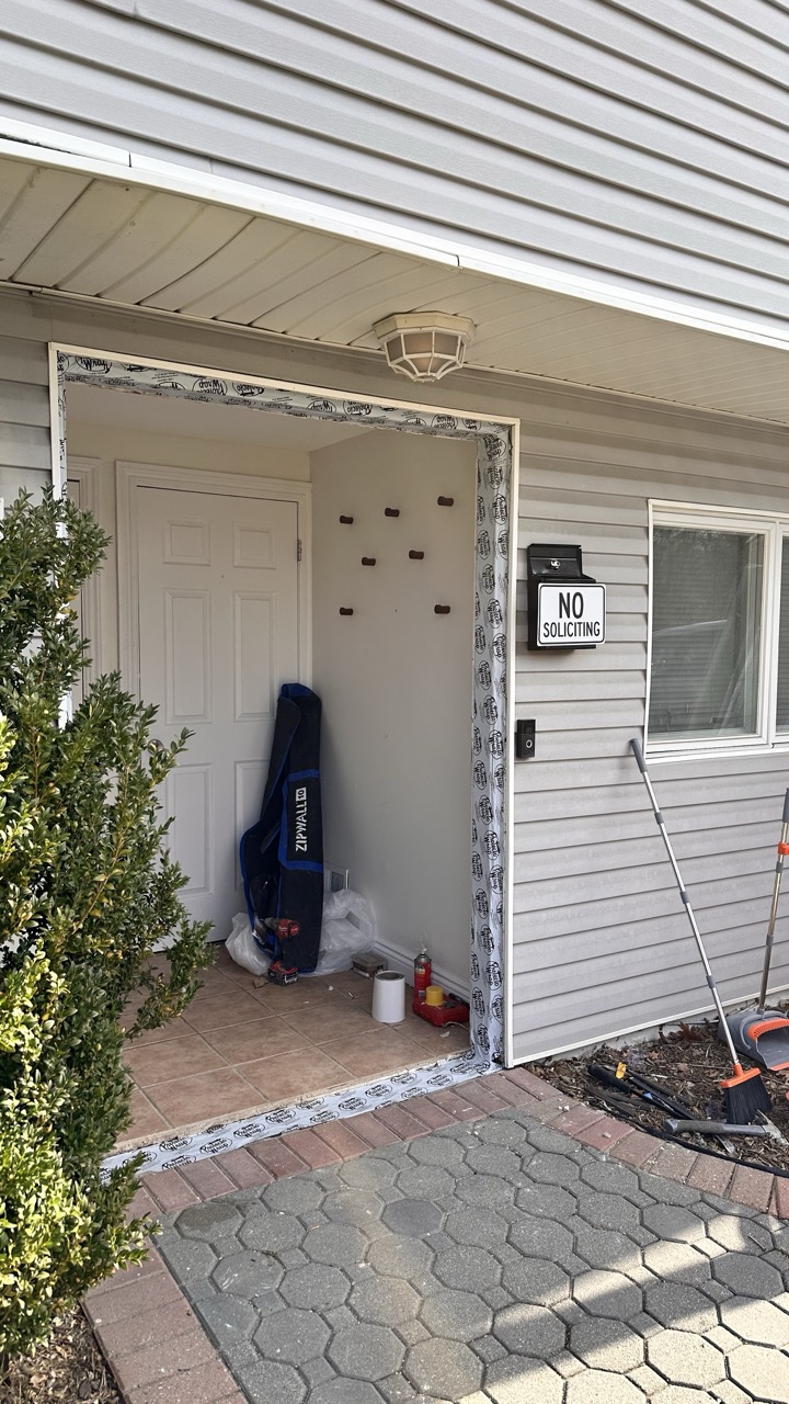 Front entrance before renovation showing old door and plastic sheeting
