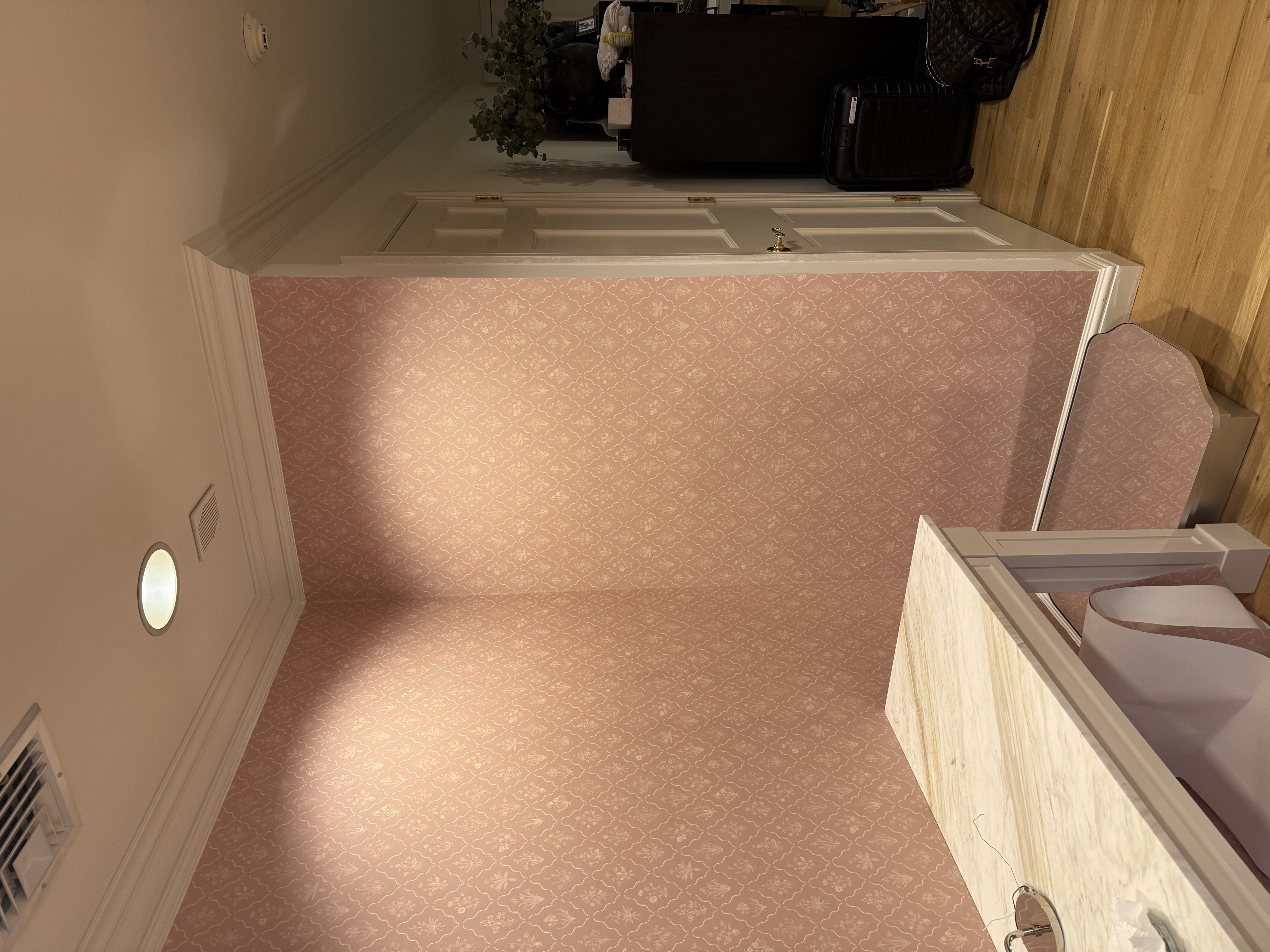 Hallway featuring pink patterned wallpaper, crown molding, marble console table, and hardwood flooring after home renovation in [City], NJ.