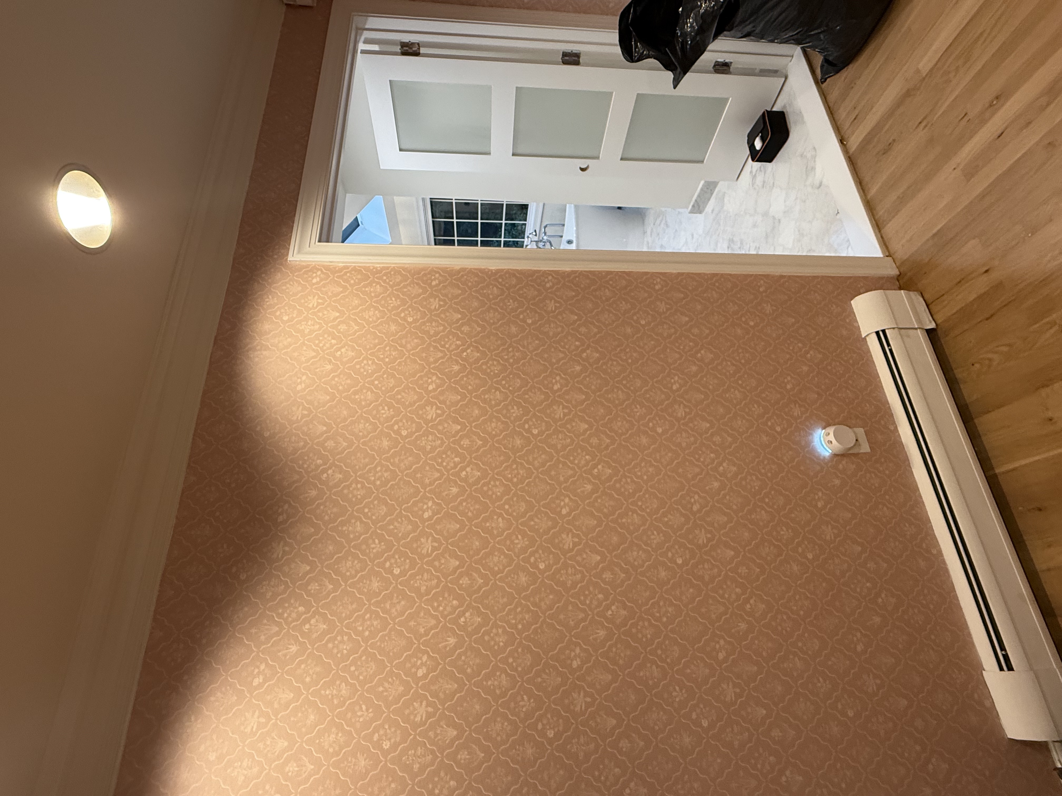 Bedroom featuring pink patterned wallpaper & hardwood flooring, with a visible bathroom beyond after home renovation in , NJ.