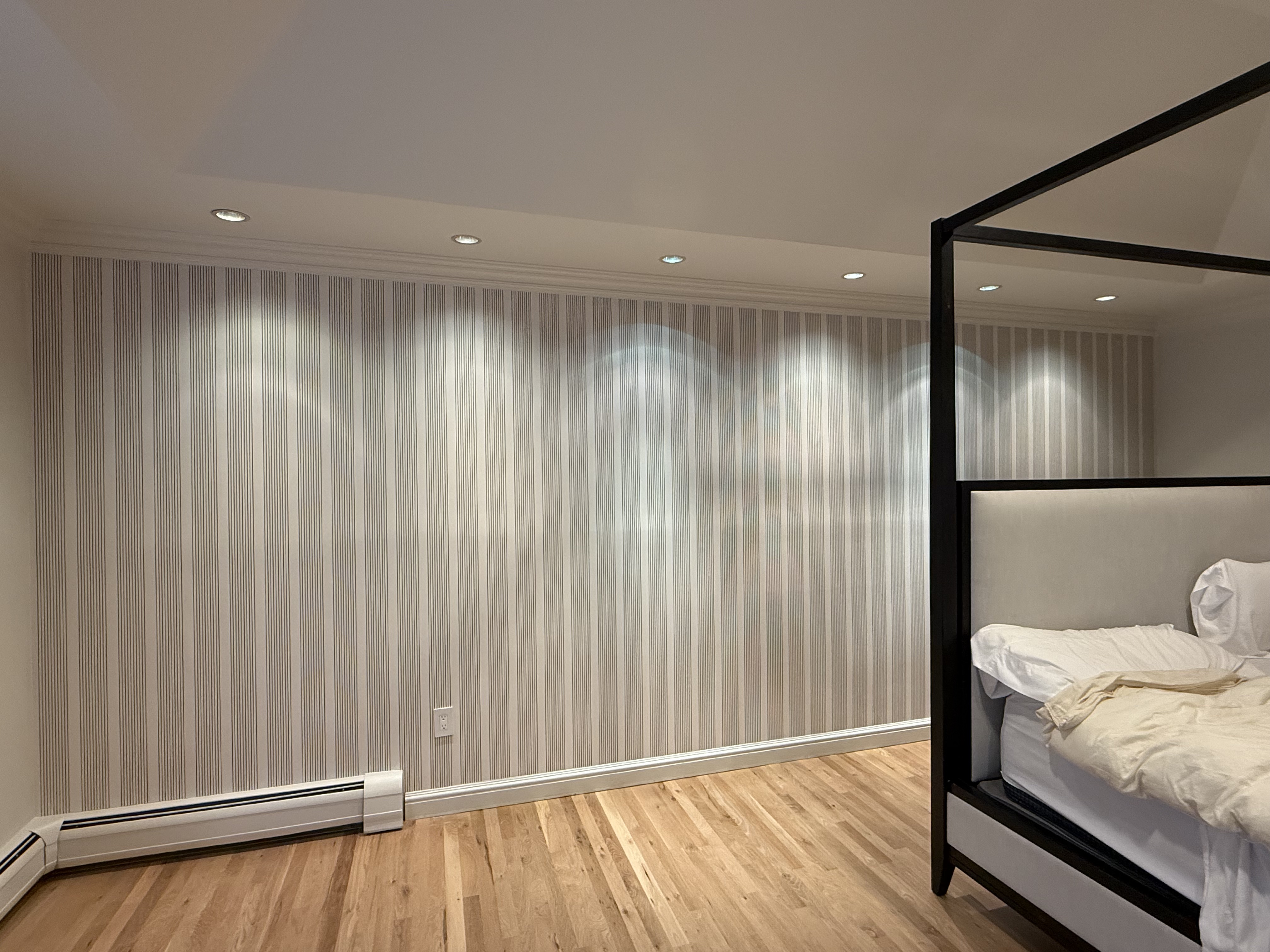 Bedroom renovation featuring striped wallpaper, natural hardwood floors, and recessed lighting in NJ.