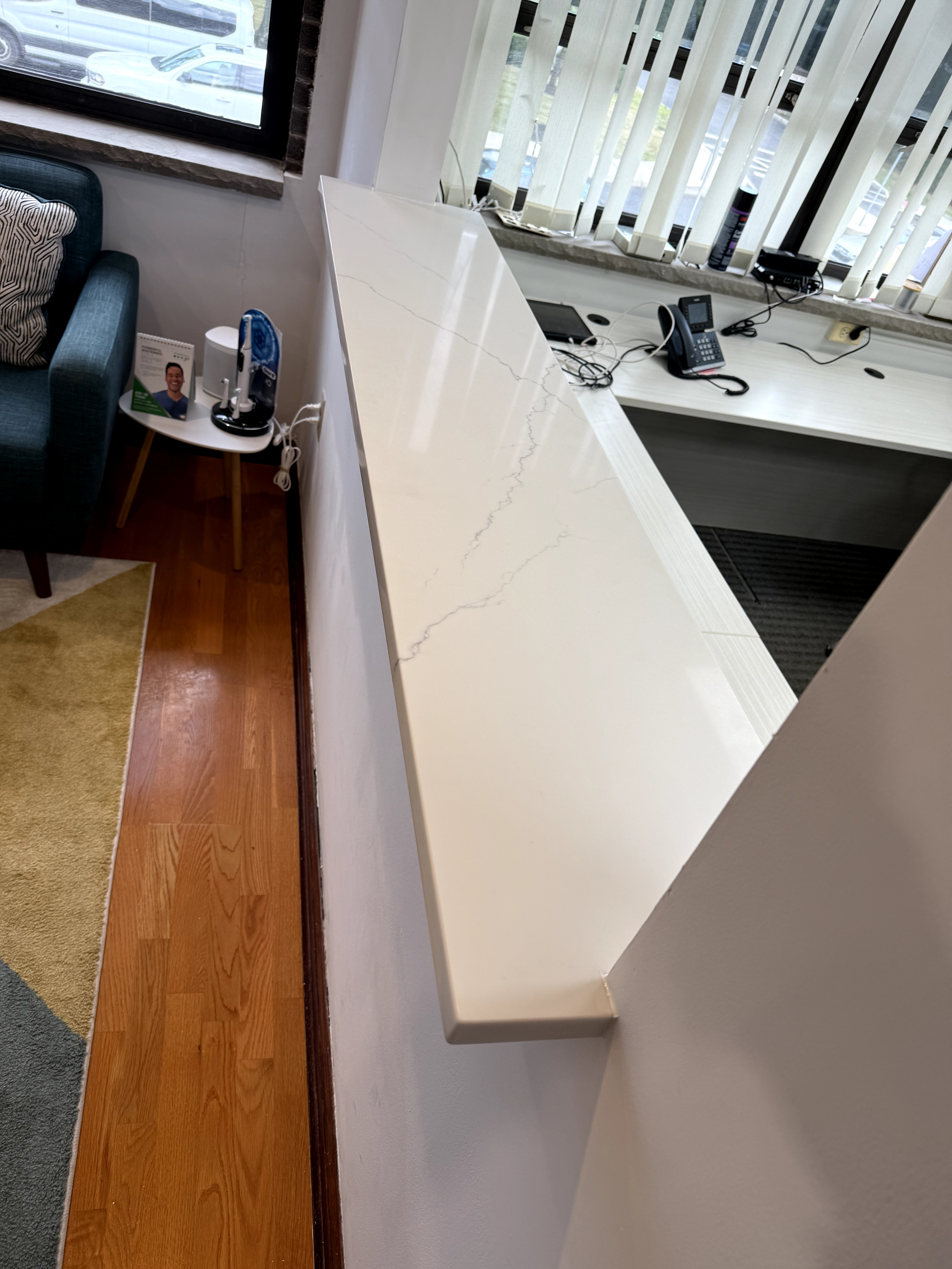Office space featuring a new white quartz counter with gray veining and light wood flooring after renovation in Rochelle Park, NJ.