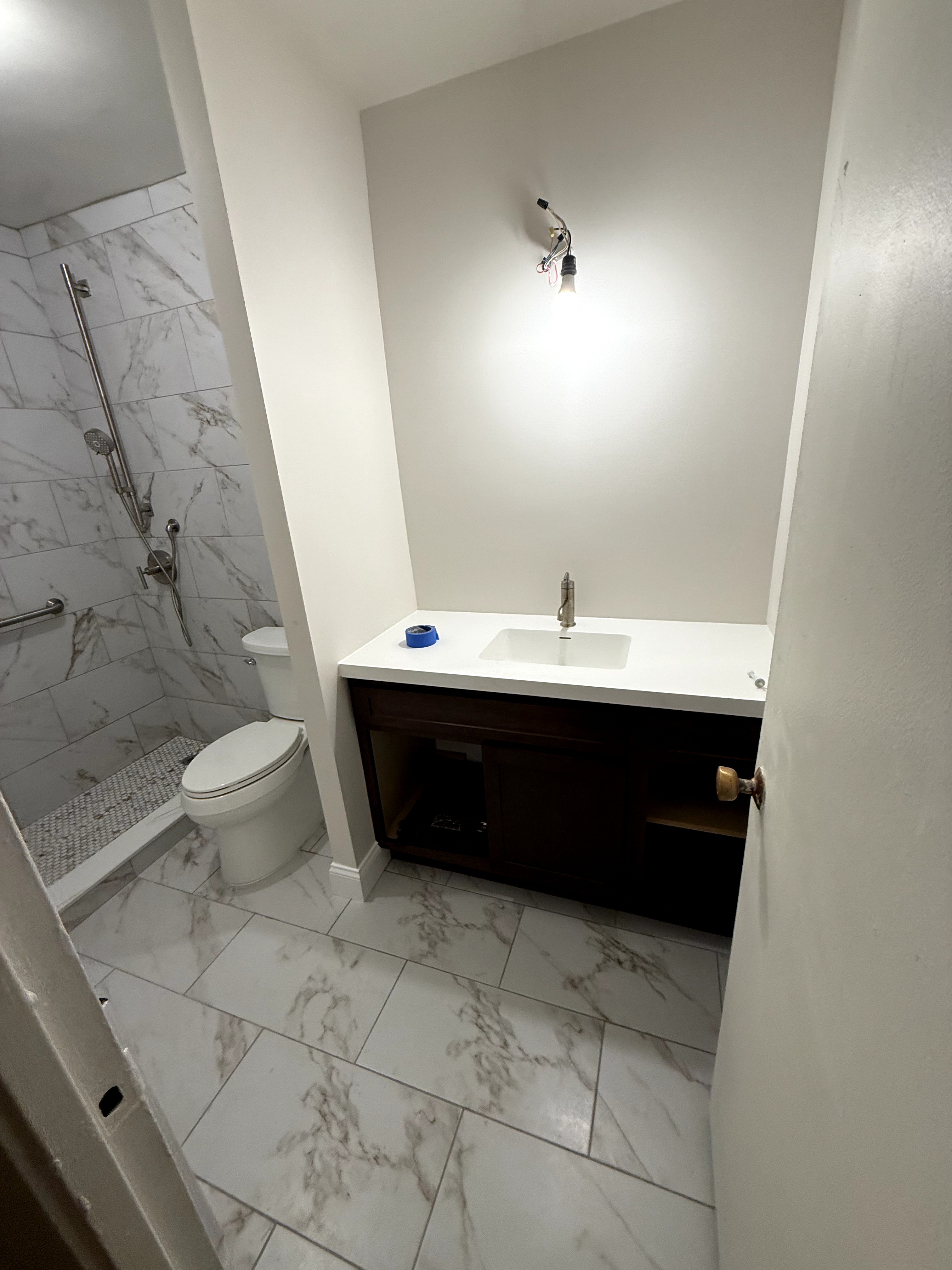 Bathroom renovation showing new vanity, toilet, and walk-in shower