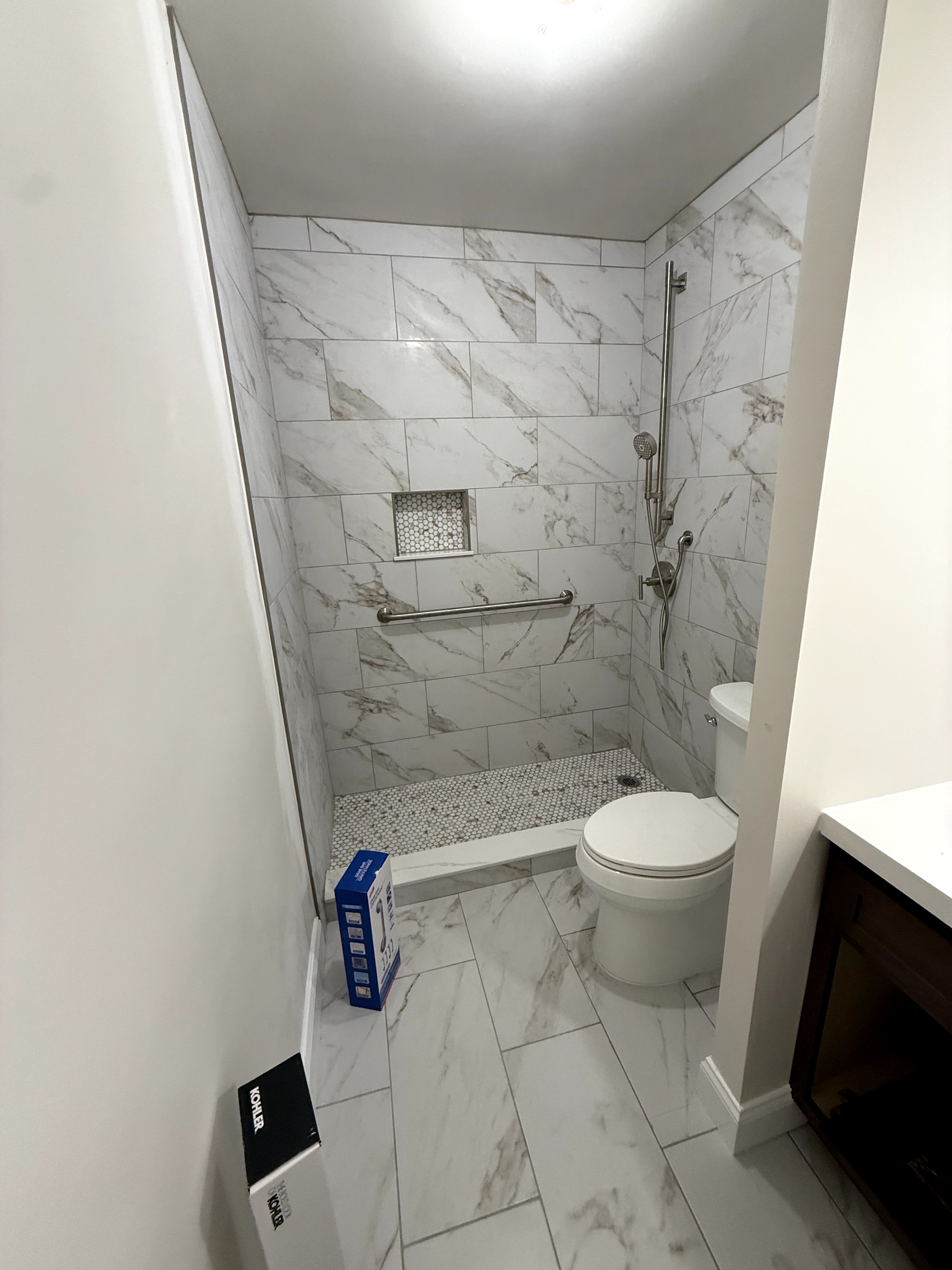 Completed bathroom renovation with marble tile, walk-in shower, and new fixtures