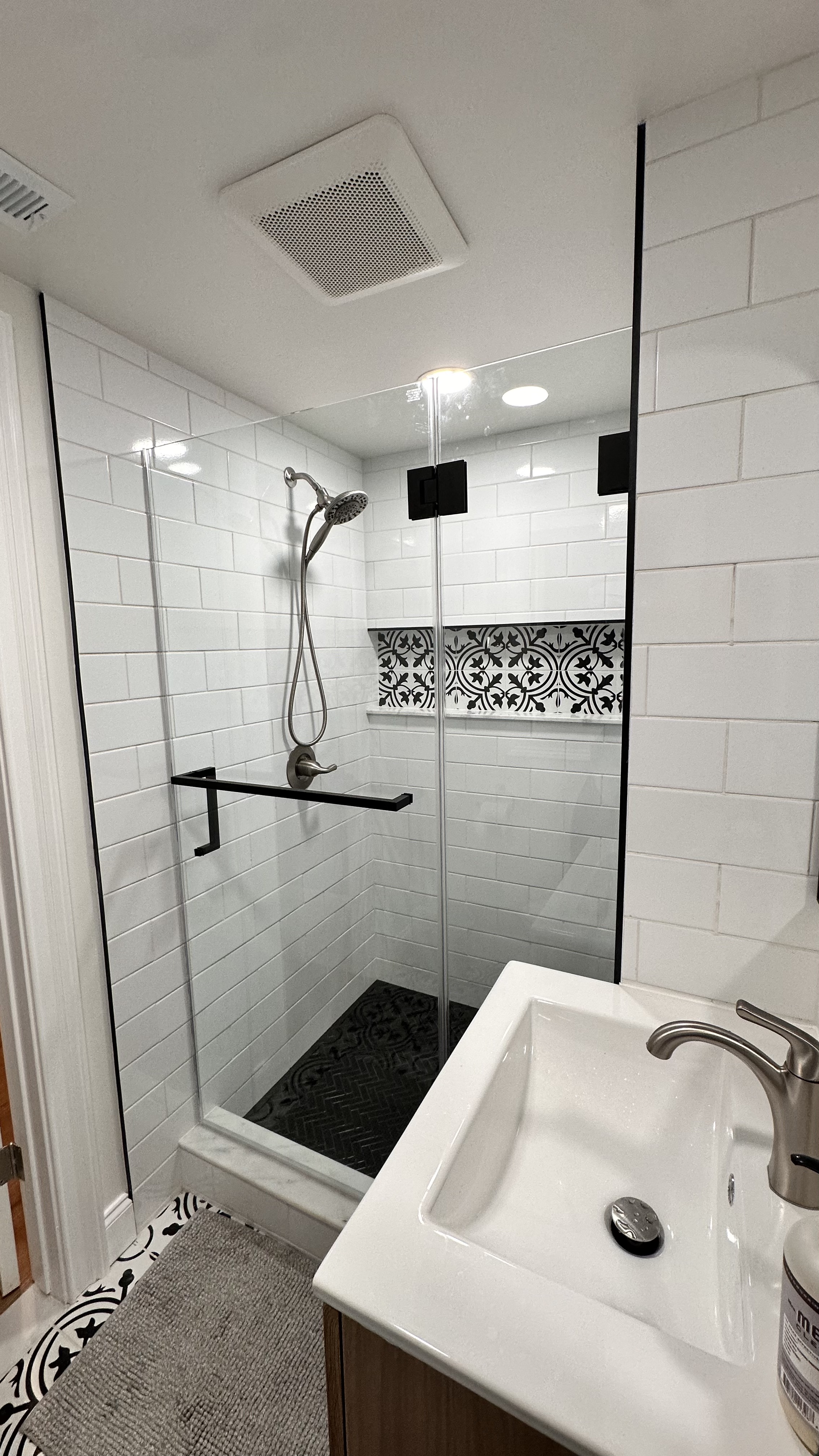 Modern bathroom with white subway tiles, patterned bath floor, glass shower, and vanity after Bathroom Renovation in West Orange, NJ.