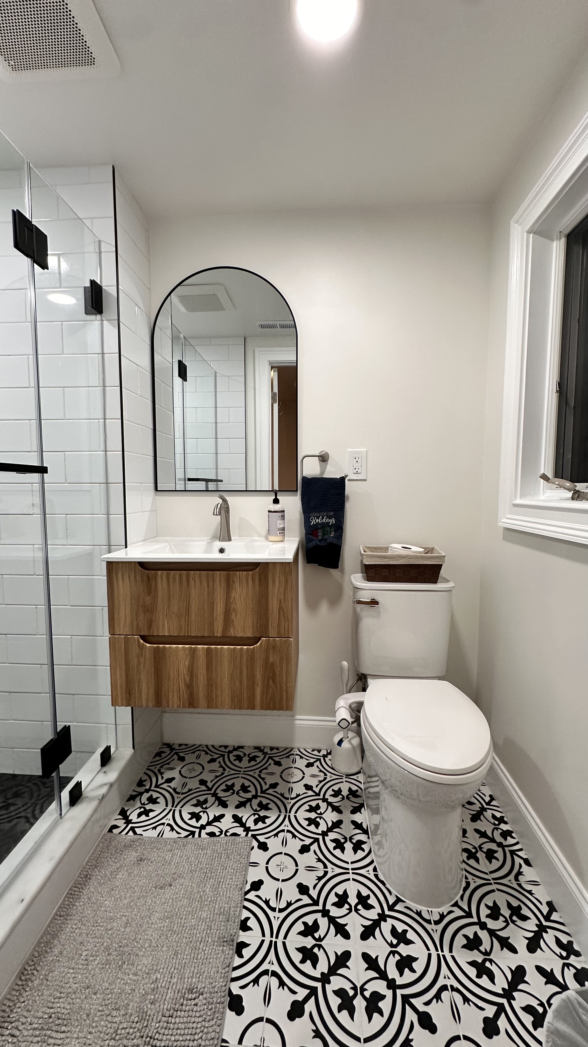 Modern bathroom with black & white patterned floor tiles, floating wood vanity, and glass shower after Bathroom Renovation in West Orange, NJ.