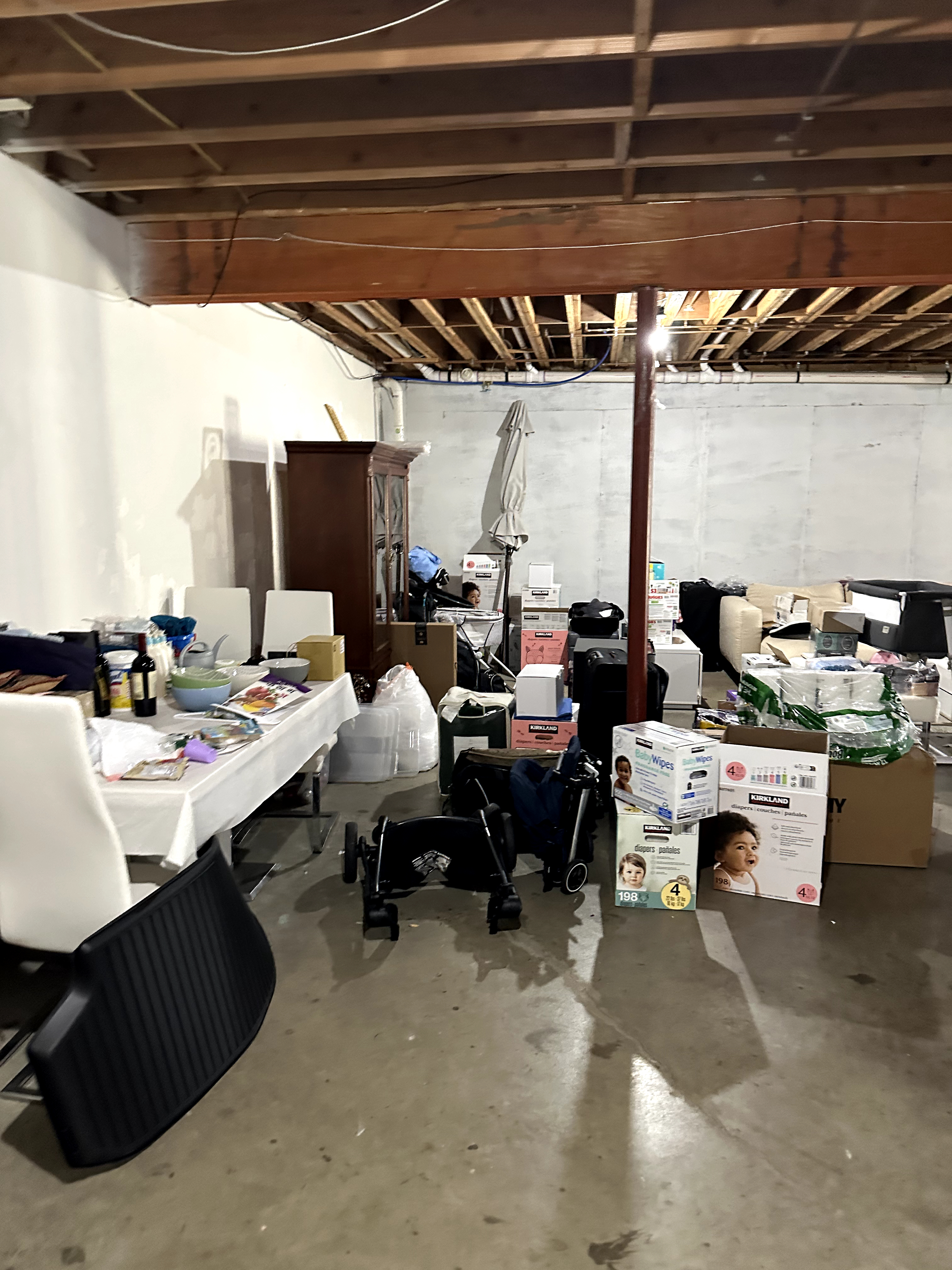 Unfinished basement with exposed wooden joists, concrete block walls, and cluttered concrete floor in Kinnelon, NJ, showing raw condition ready for renovation.