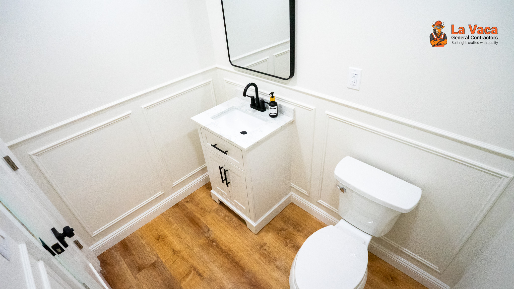Powder room with wood-look flooring, white wainscoting, vanity with marble countertop after Basement Finishing in Kinnelon, NJ