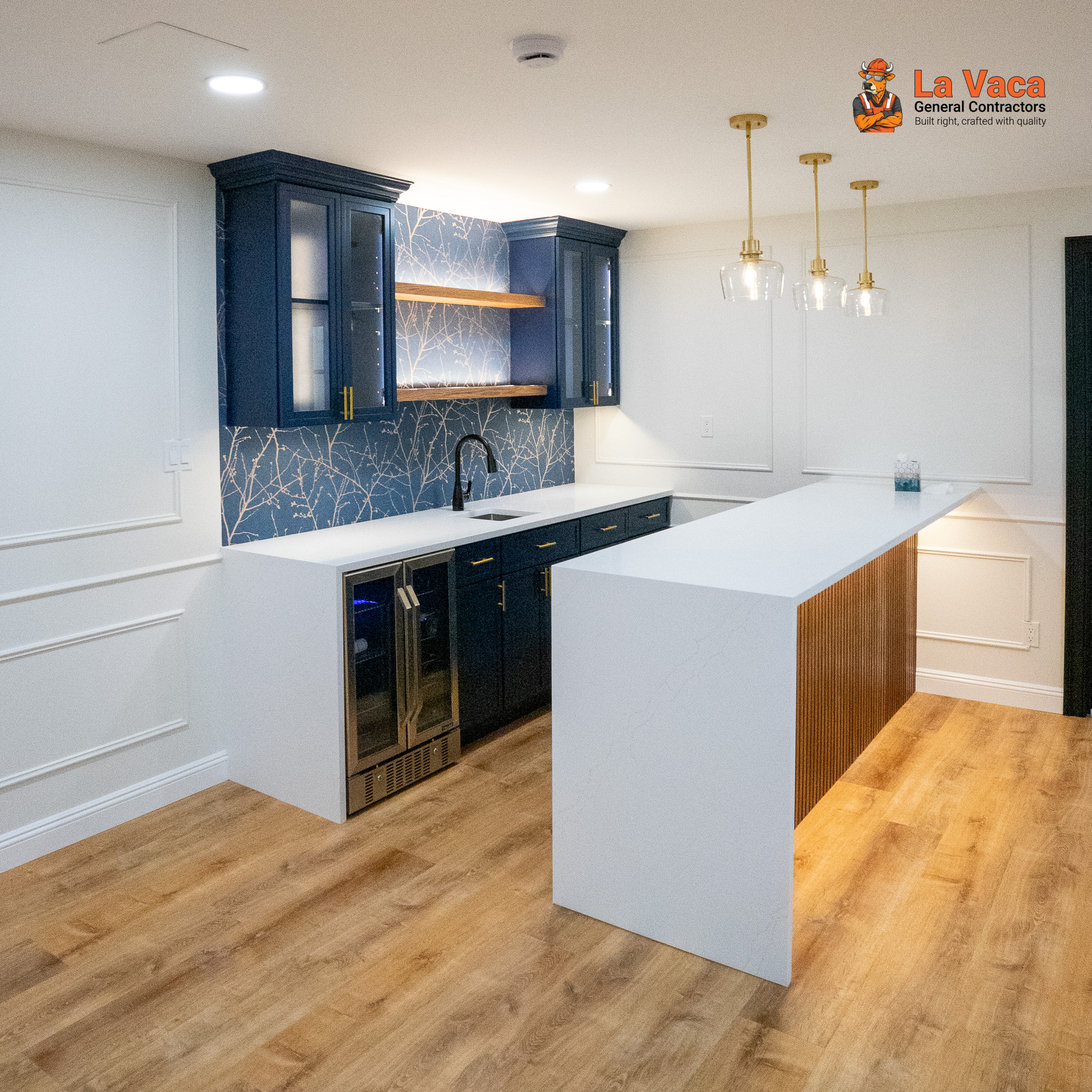 Basement wet bar with blue cabinets, white quartz countertops, and wood flooring after Basement Finishing in Kinnelon, NJ.