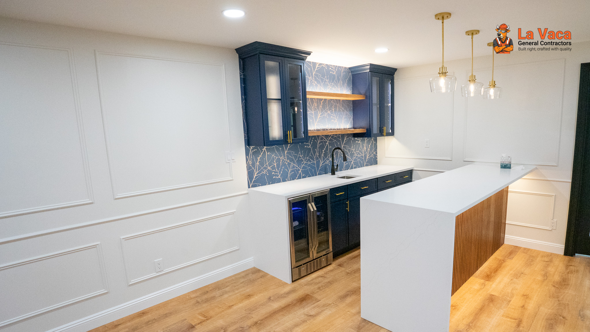 Basement bar featuring navy cabinets, white quartz, wood paneling, and decorative white trim after Basement Finishing in Kinnelon, NJ.