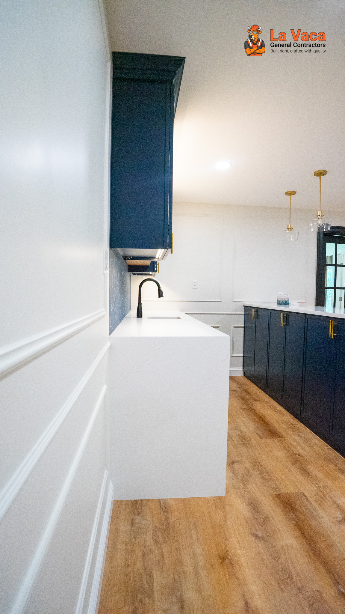 Basement bar/kitchenette with navy cabinets, white quartz countertops, and wood flooring after Basement Finishing in Kinnelon, NJ.