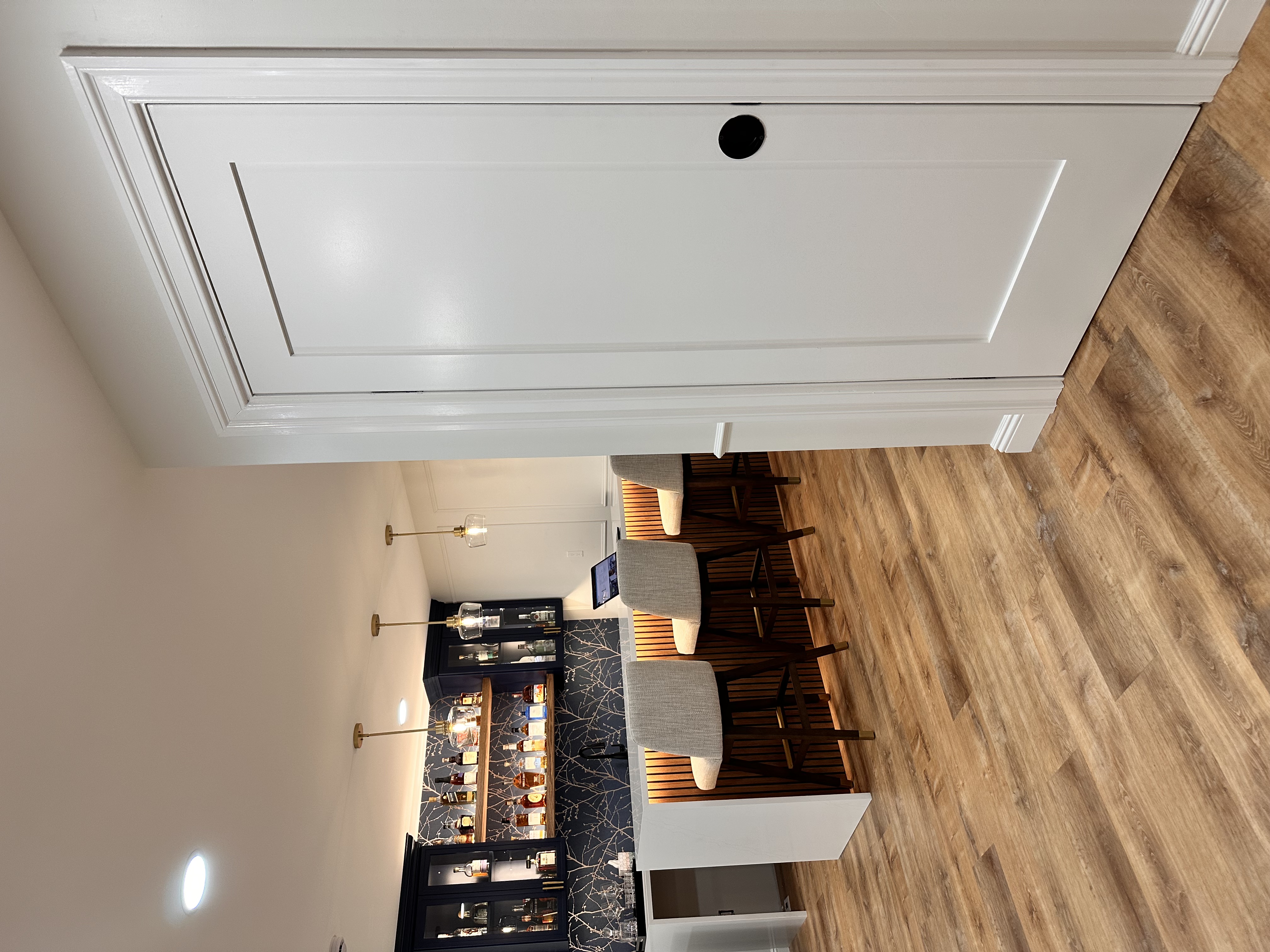 Basement bar featuring dark blue cabinetry, quartz countertop, wood-look flooring, and pendant lighting after Basement Finishing in Kinnelon, NJ.