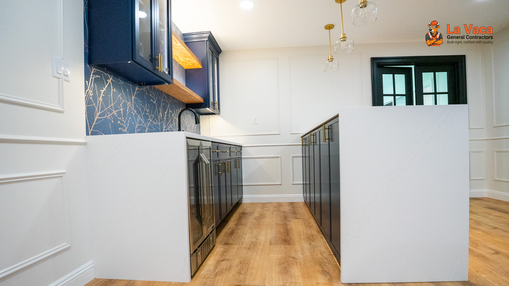 Luxurious basement bar with navy cabinets, white quartz countertops, wood shelving & black wrought iron bar stools after Basement Finishing in Kinnelon, NJ